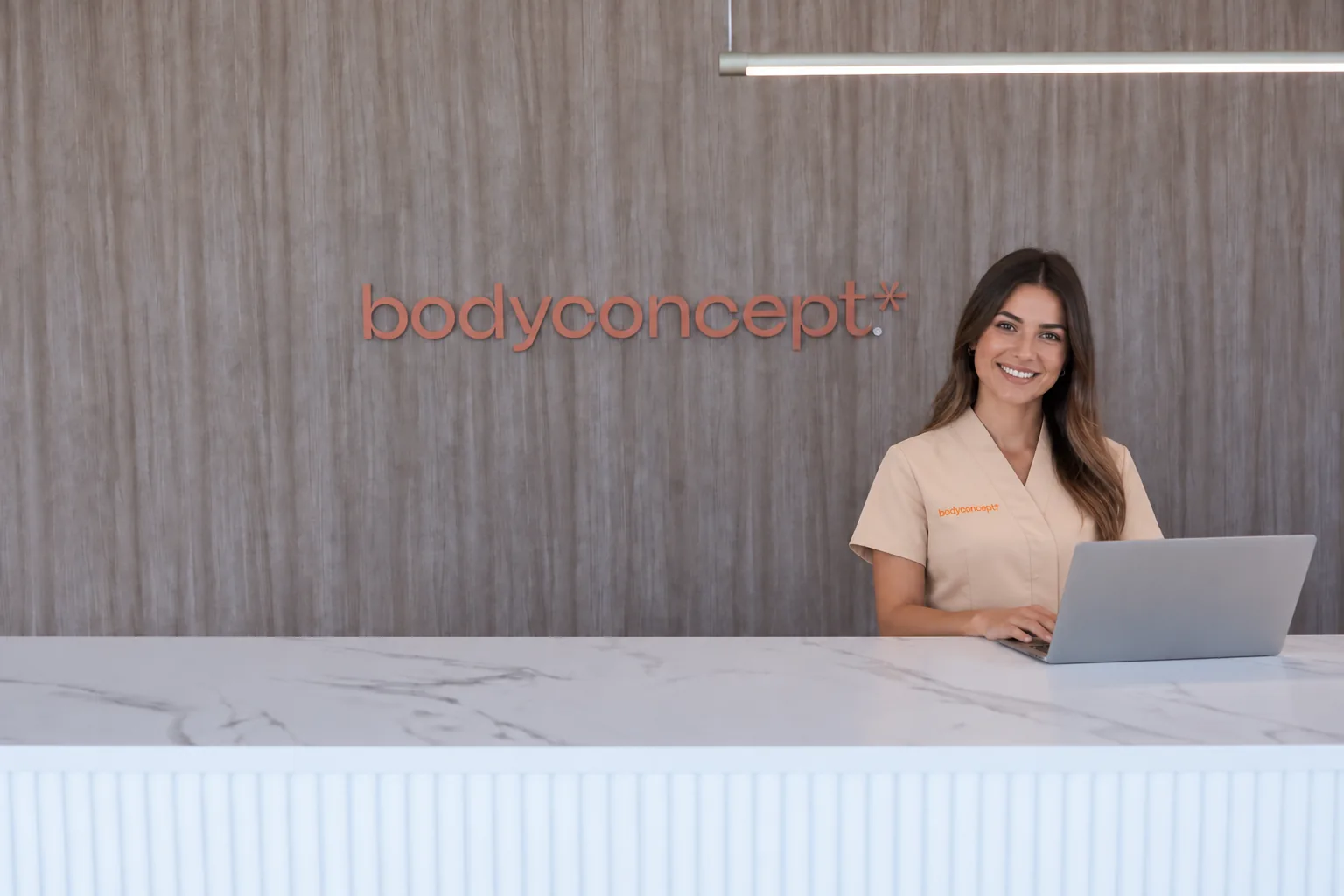 Colaboradora BodyConcept ao computador no balcão da clínica